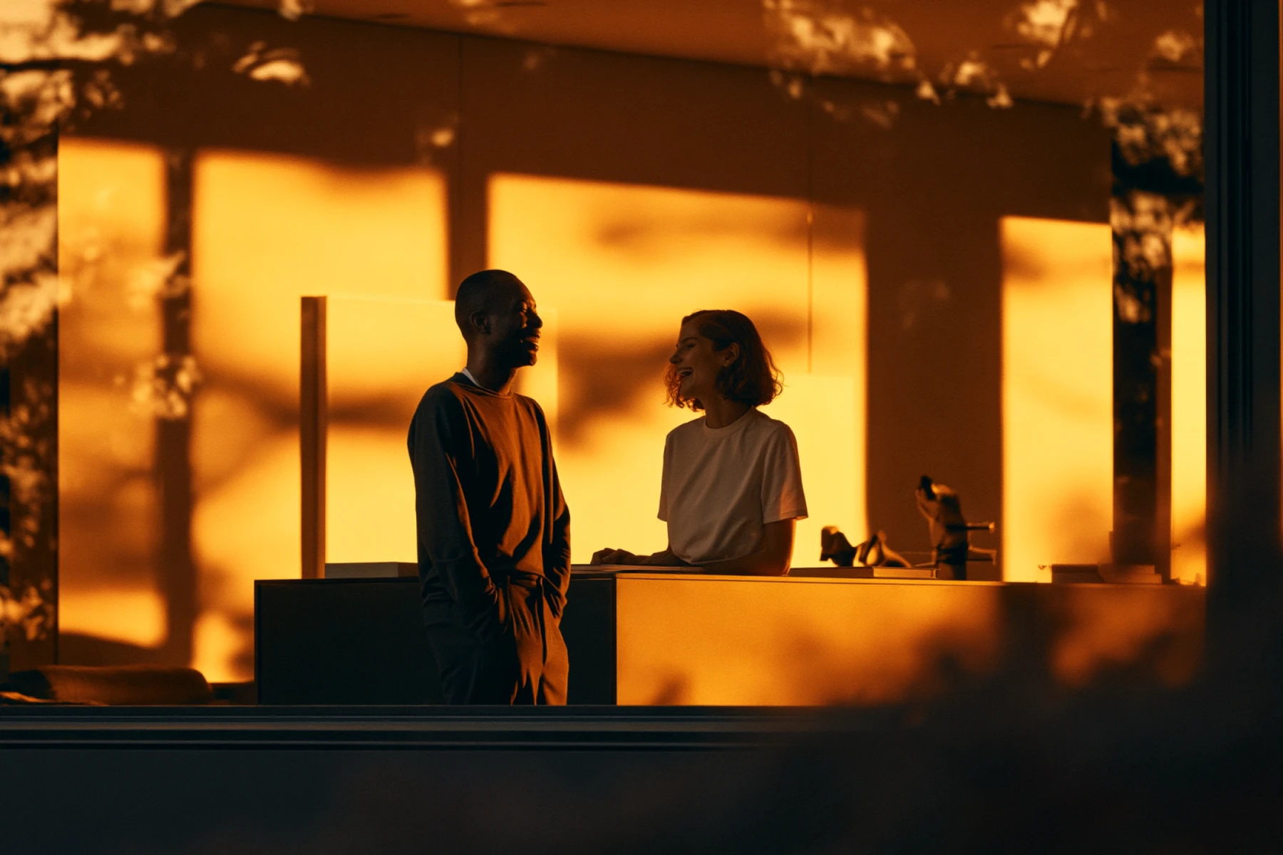 Two people talking and laughing at a desk in golden-hour light